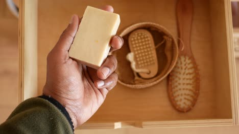 hand holding soap bar in wooden drawer with other natural care products