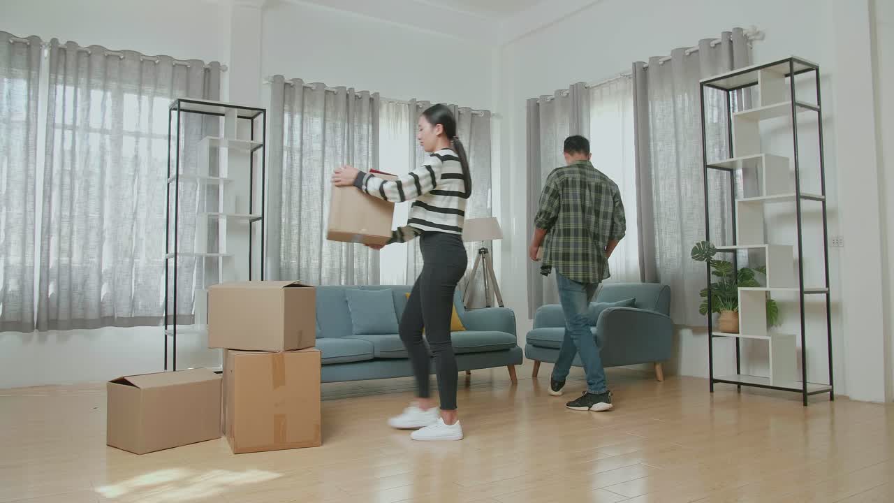 un hombre sentado en el sofá para descansar mientras una mujer de pie y mirando a su alrededor después de que llevan cajas de cartón con cosas en una nueva casa