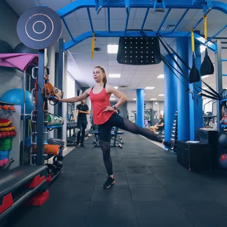 young woman doing exercise in the sports gym. sporty female training her legs on the background of modern fitness club.