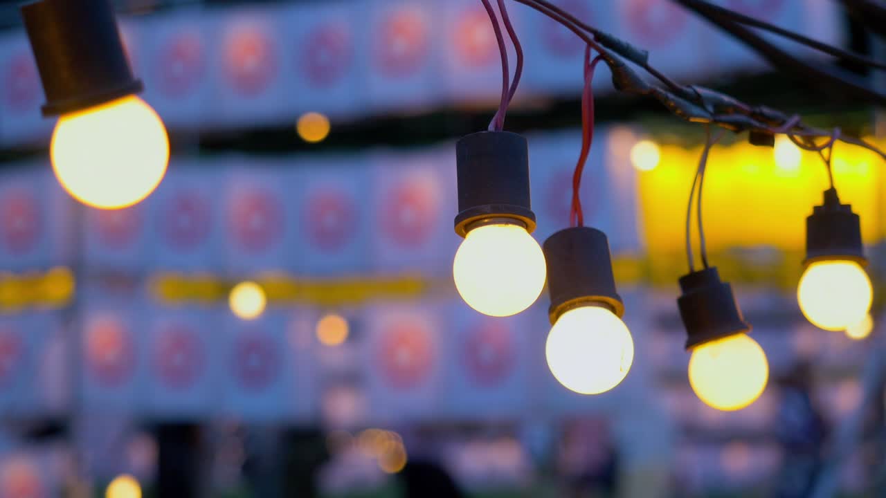 personas caminando a través de la bombilla colgante iluminada en el día del festival de verano