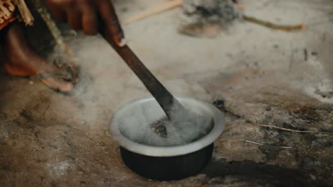 Steam-emitted-from-roasting-coffee-in-metal-bowl---African-person-stirring