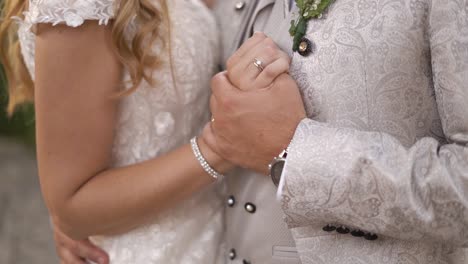 groom and bride holding hands showing wedding rings, stylish clothes, slow motion shot