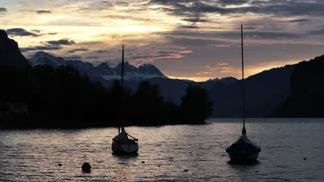 boats on lake walensee moored in the village of weesen. silhouettes of boats swaying on the water at sunset. schweiz