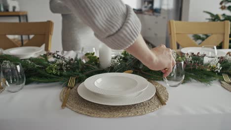 un primer plano de dos personas preparando la mesa en casa para la víspera de navidad.