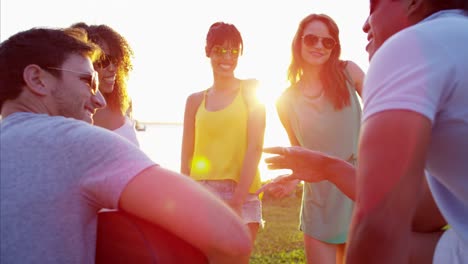 amigos multiétnicos disfrutando de una fiesta en la playa al atardecer.