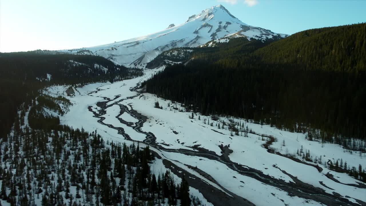 US, Oregon, Mt Hood, White River, 2025-04-22 - Drone view of Mt Hood at sunset over the White River in spring, with snow still covering the mountain and creek and trees