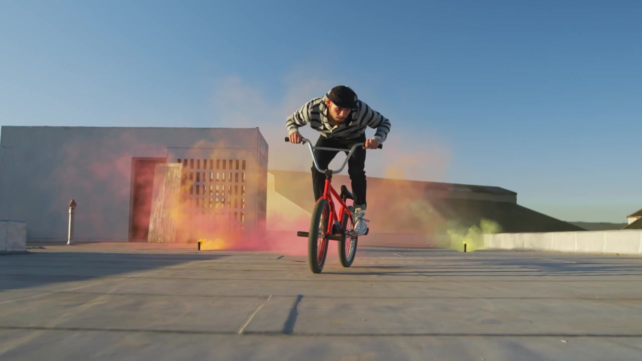 Rowerzysta BMX wykonujący akrobacje z kolorowymi efektami dymu