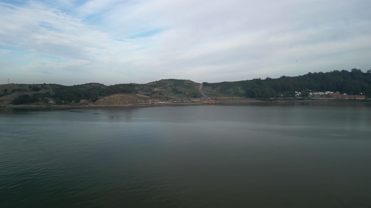Serene drone footage of Point Molate Beach, with gentle waves lapping against the shoreline under golden sunlight.