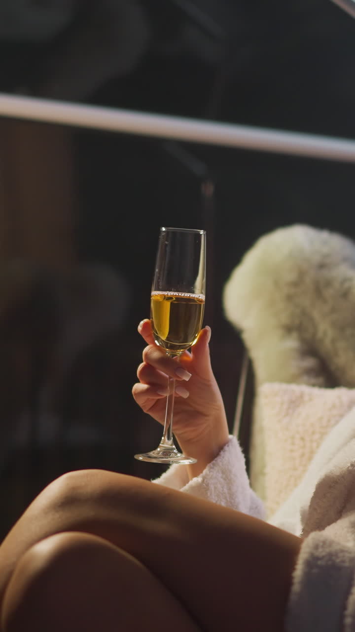 지친 여성은 큰 파노라마 창문이 있는 발코니에서 페인 잔의 얼룩을 아 니다. 여자는 부드러운 의자에 앉아 알코올 음료를 마시며 휴식을 취합니다.