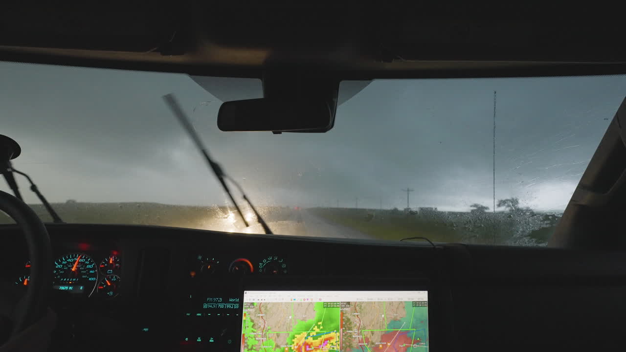Inside Vehicle View Of Storm Chasers Driving Through Heavy Rain With Radar Screen