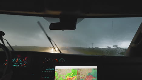 inside vehicle view of storm chasers driving through heavy rain with radar screen
