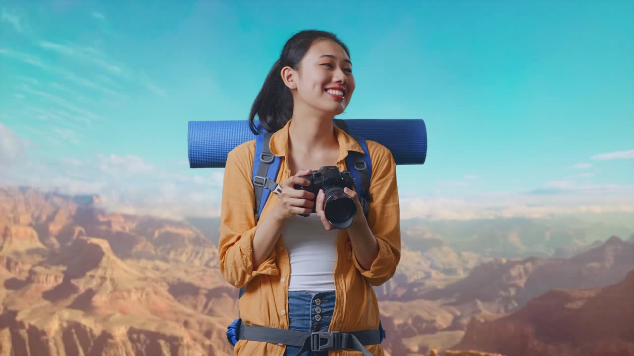 Asian Female Hiker With Mountaineering Backpack Smiling And Holding A Camera In Her Hands Then Looking Around While Traveling At The Top Of Mountain