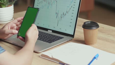 man use mobile phone with green screen display, financial data with graphics and charts on a laptop computer, video in 4k