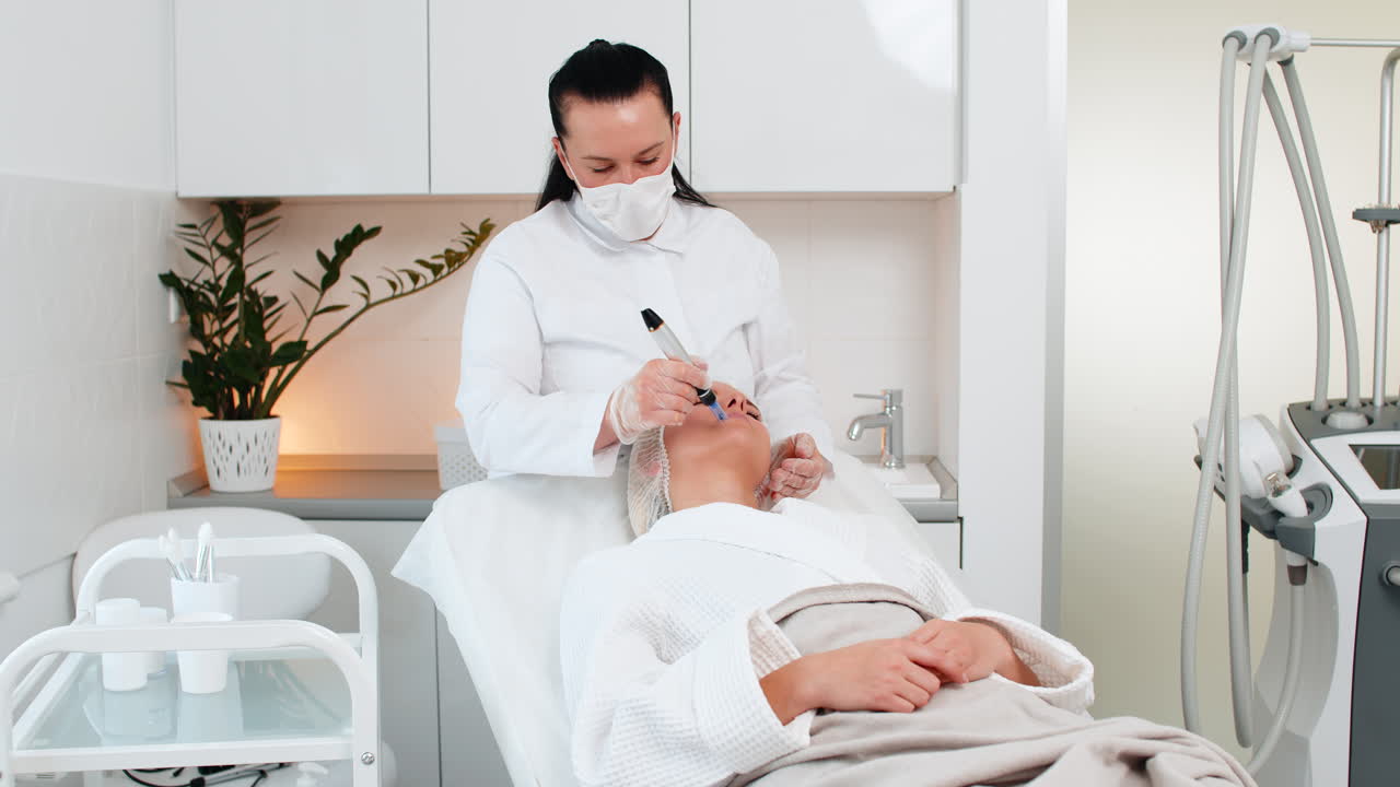 Ahli kecantikan melakukan microneedling dermapen pada kulit dahi wanita muda di klinik kecantikan