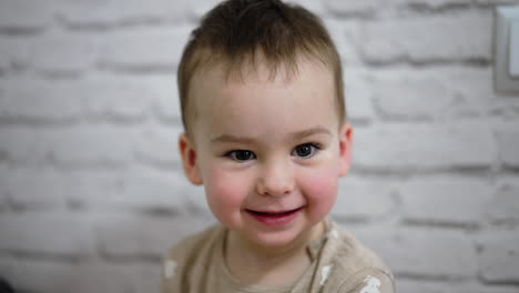 charming little caucasian boy smiling adorably to the camera. close up portrait of a one year toddler.
