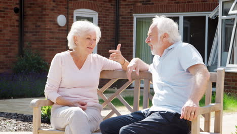 Retired-Couple-Sitting-On-Bench-And-Talking-In-Assisted-Living-Facility