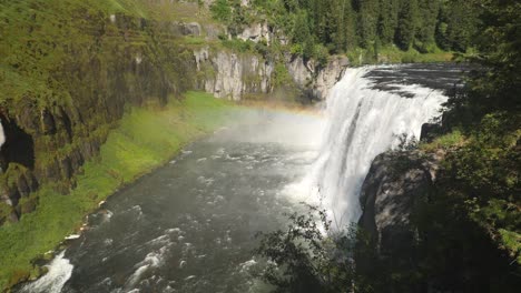 spectacular panoramic scene of famous upper mesa falls waterfall cascading down side of mountain steep high cliff with green mossy tree lined mountainside in background, idaho, static profile