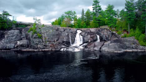 Rauschender-Wasserfall-Stürzt-Durch-Natürliche-Felsklippen-Im-Norden-Ontarios-Mit-Wald-Und-Bewölktem-Himmel