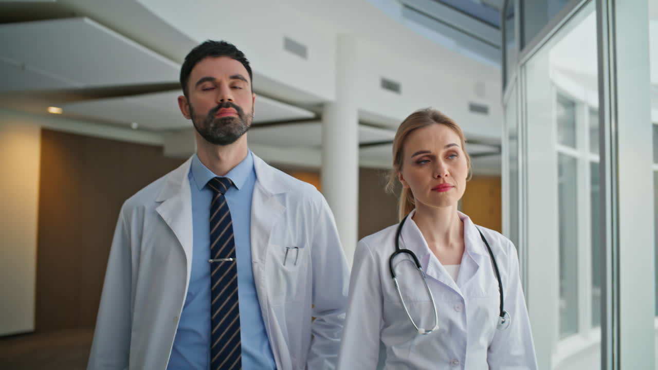 Primo piano di medici fiduciosi che camminano nel corridoio dell'ospedale. Due professionisti in clinica.