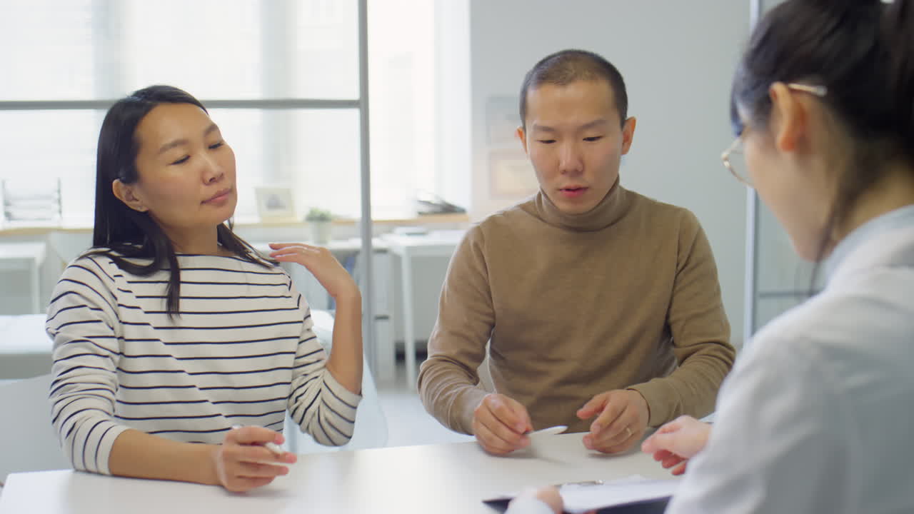 Asian Couple Signing Contract in Pregnancy Clinic