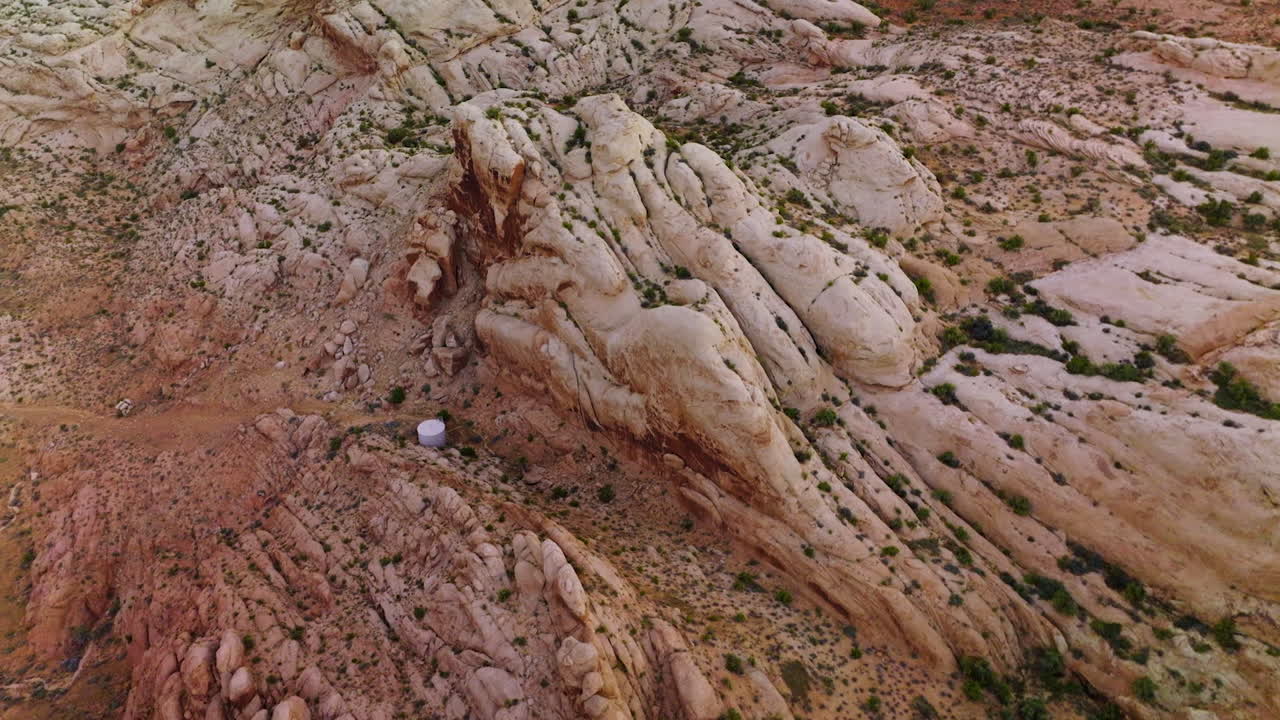 Flying over bare rounded rocks in the canyons of Utah, USA. Good highways in the deserted landscape among the mountains. Aerial view.