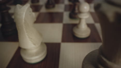 closeup of white wood chess set pieces come into view as chessboard rotates