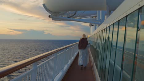 vista de una mujer caminando en la cubierta lateral y disfrutando de la puesta de sol desde un crucero