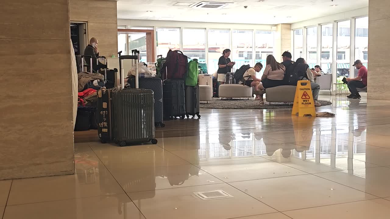 Several hotel guests with their luggage queuing at the hotel's lobby.