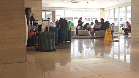 several hotel guests with their luggage queuing at the hotel's lobby.