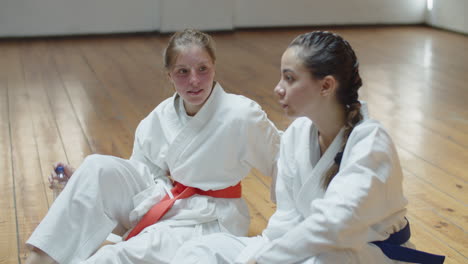 ręczne ujęcie dziewcząt siedzących na podłodze po treningu karate