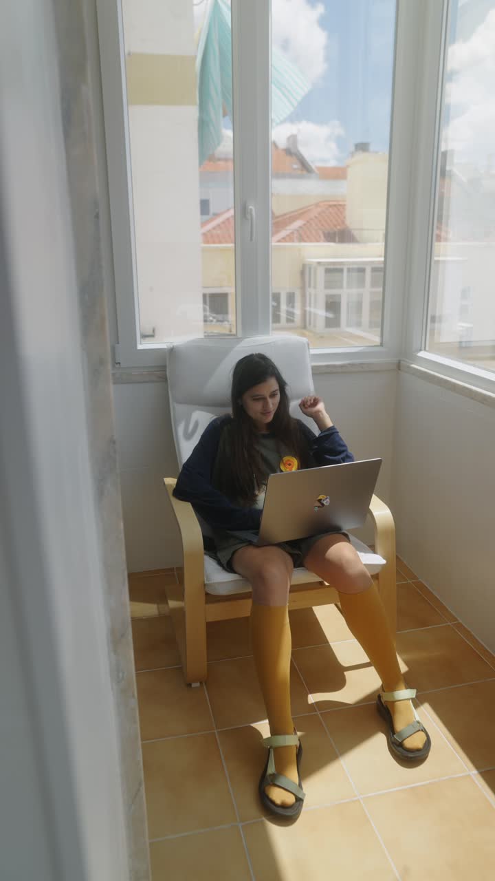 Teenage girl working on a laptop on a balcony
