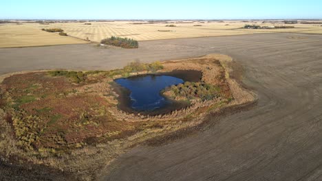 Aerial-4k-footage-flying-over-small-deep-blue-pond-in-north-American-countryside