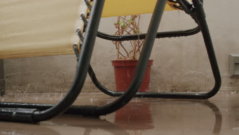 a yellow chair and a flower are getting wet on the balcony in the rain
