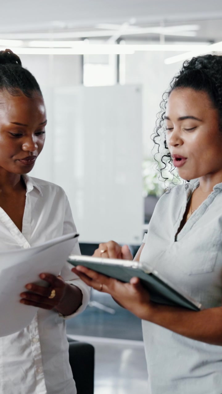 Two Professional Women Discussing Business Documents in a Modern Office