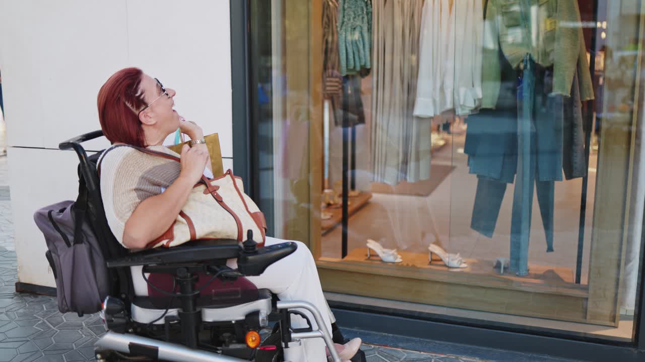 Donna felice su sedia a rotelle elettrica che guarda le vetrine in un negozio