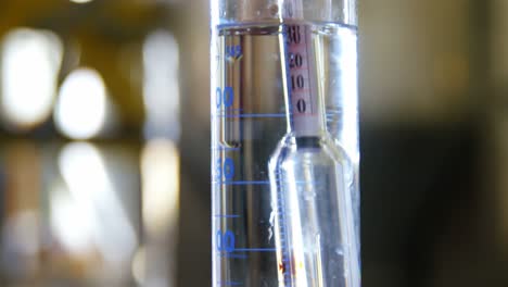 male worker examining gin in measuring cylinder 4k