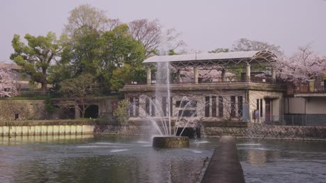 Fuente-Inclinada-De-Keage-En-Kioto,-Japón,-Sakura-De-Primavera-En-El-Fondo