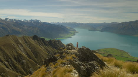 fit woman running to jagged cliff looking at southern alps mountain range