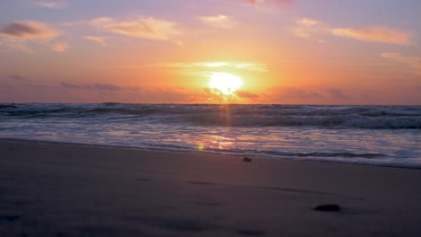 beautiful sunset on the background of baltic sea, sun going beyond the horizon illuminating water and clouds in the sky, calm sea waves, romantic mood, copy space, low wide shot