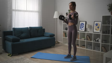 Mujer-Joven-Con-Cola-De-Caballo-Está-Levantando-Pesas-En-La-Sala-De-Estar-Entrenando-En-Casa-Fitness-Y-Bienestar-Estilo-De-Vida-Saludable-Movimiento-Plano-Panorámico