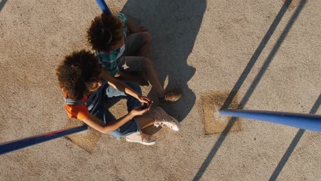 madre e hijo usando el teléfono en el patio de recreo
