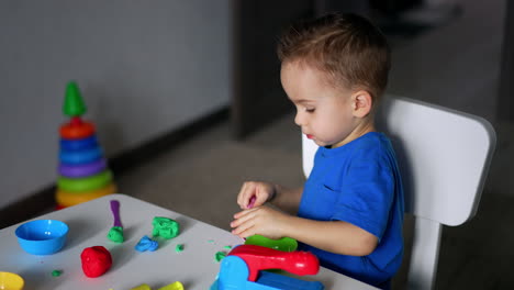 little toddler is totally absorbed by his game. useful hobby of sculpturing with plasticine.