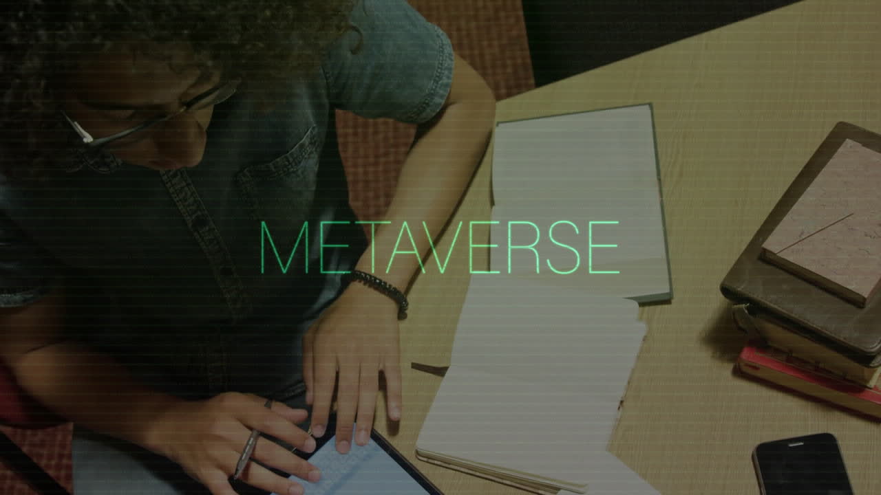 Using tablet with animation of METAVERSE text, person at desk with books