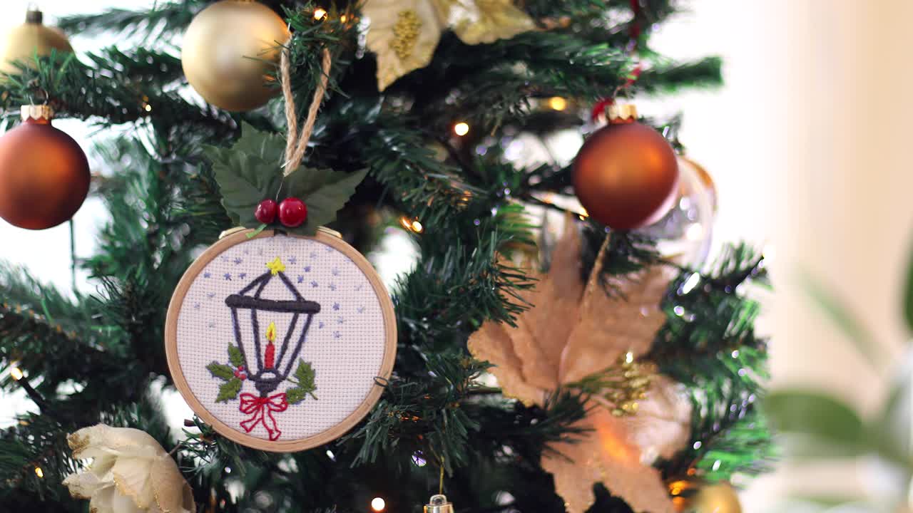 manos de niña poniendo ornamentación bordada en el árbol de navidad