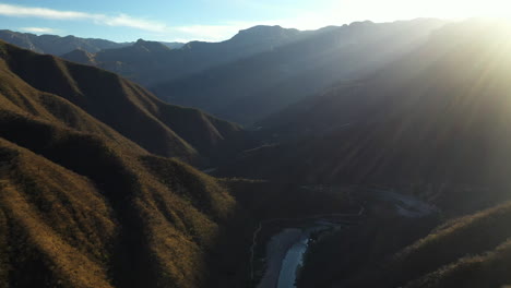 sun setting behind mountain landscape of copper canyon, mexico, forward aerial