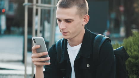 young student using mobile phone outdoors.