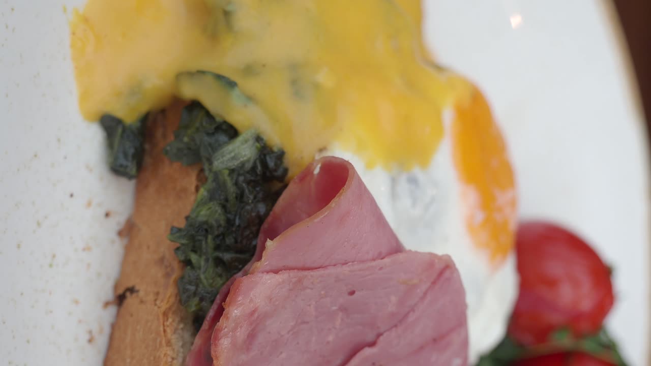 Close-up of a gourmet breakfast or brunch plate with ham, spinach, egg, and toast