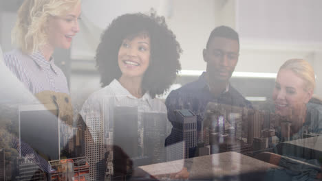 Composite-of-happy-diverse-colleagues-clapping-at-meeting,-and-modern-cityscape