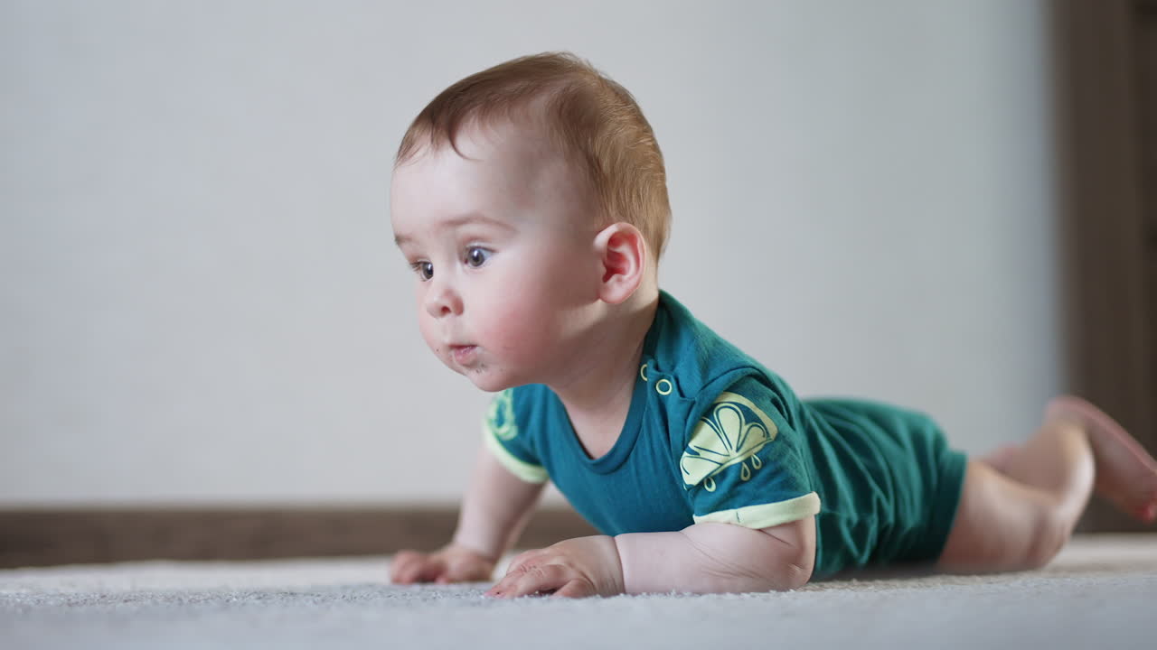 Nice cute baby boy trying to crawl over the floor. Child looks straight ahead attentively trying to reach a toy.