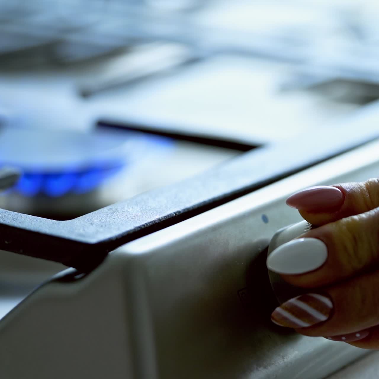 Turning the gas stove. Woman's hand turning on the fire on gas burner in the kitchen. Slow motion.